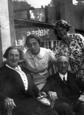 Four people in front of a window, two standing and two sitting.
