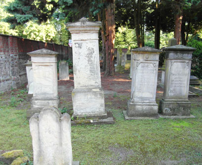 Several gravestones on partly green and partly bare ground;